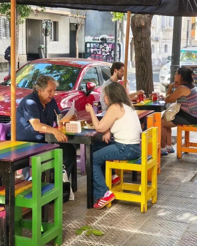 Personas comiendo en las mesas y sillas de colores de la terraza