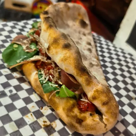Sándwich Pizzabella con jamón serrano, tomate cherry asado, parmesano y rúcula